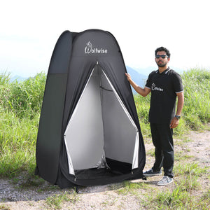 A male model standing next to WolfWise pop up shower tent. 